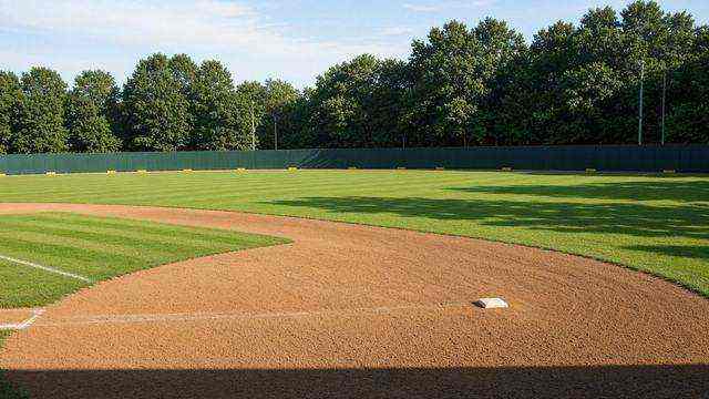 Single-A ballpark infield and outfield wall under afternoon light
