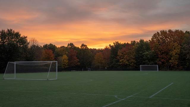 An empty high school soccer field with goals at dusk.